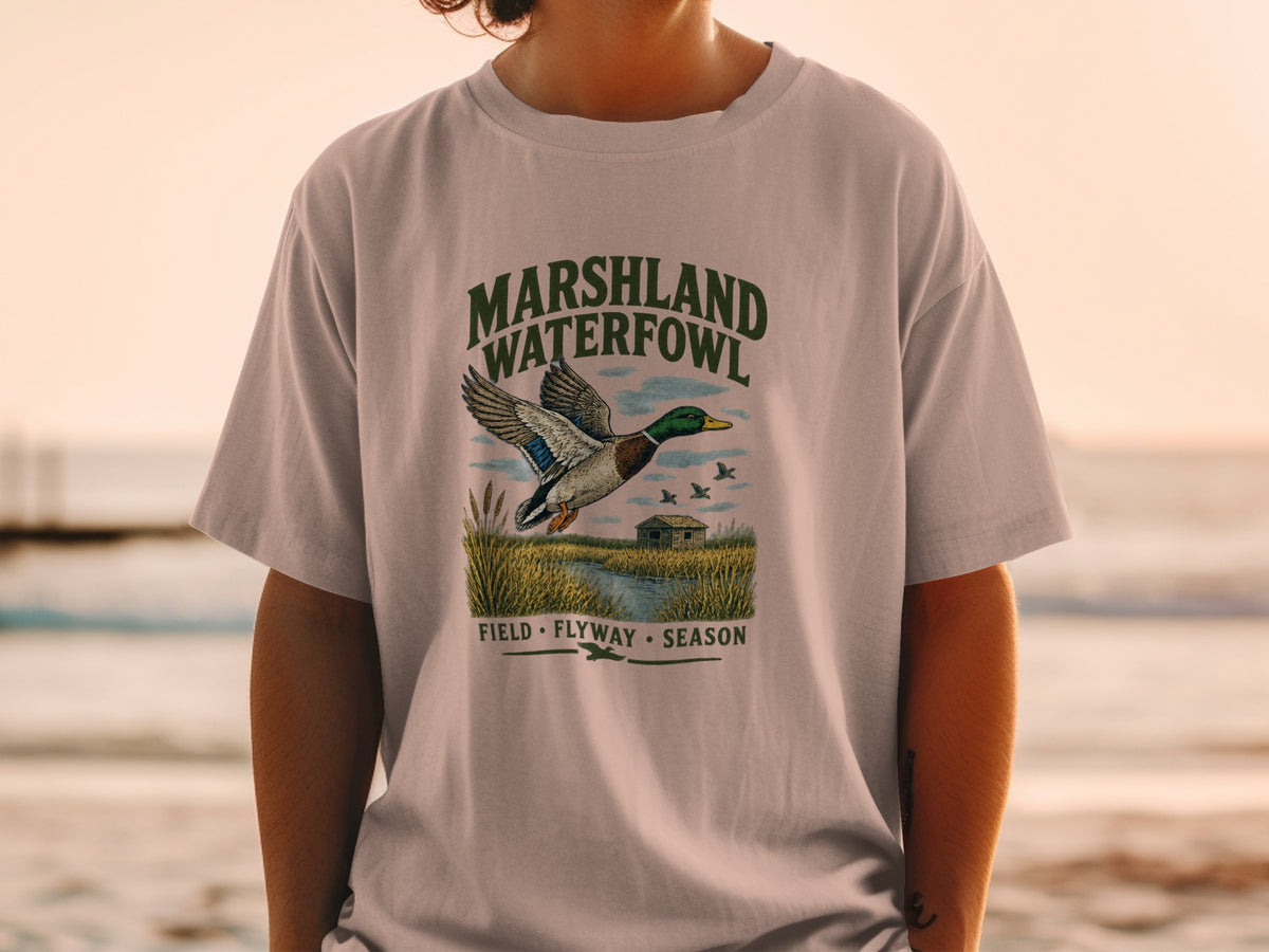 T-shirt graphic with mallard duck flying over marshland, "MARSHLAND WATERFOWL" text.