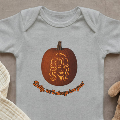 Baby bodysuit with a jack-o-lantern carved with Dolly Parton's face and orange text.