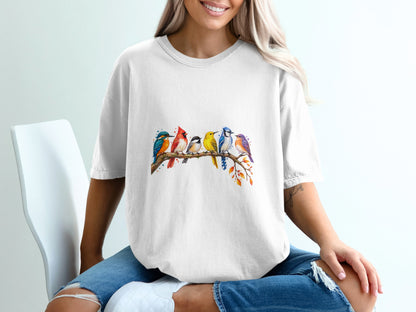 Watercolor illustration of seven colorful birds perched on a branch on a white t-shirt.