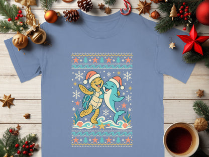 Blue t-shirt with a cartoon turtle and dolphin wearing Santa hats in a winter sea pattern.