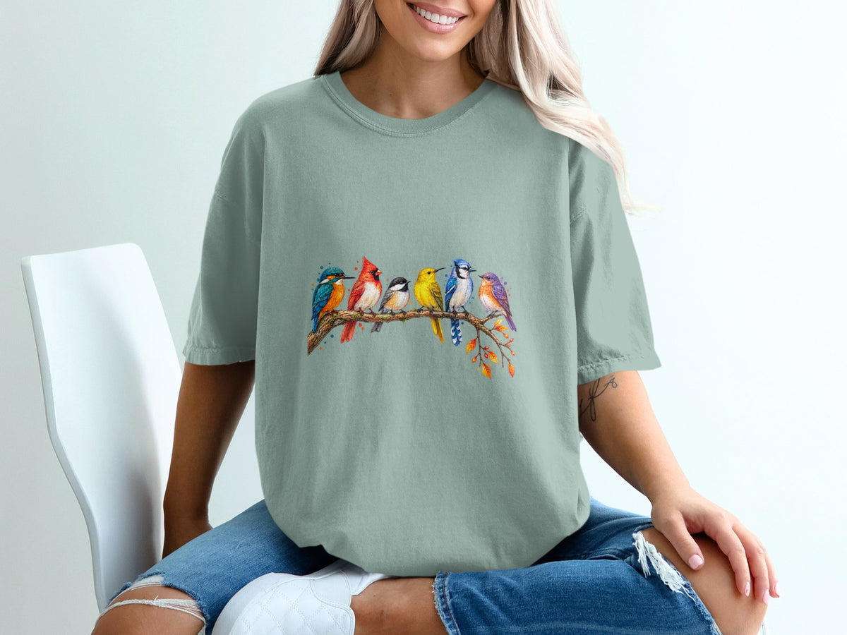 T-shirt with watercolor painting of seven colorful birds perched on a branch.