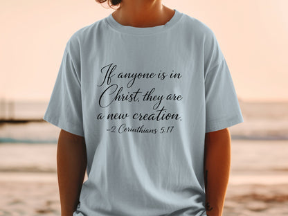 Light blue t-shirt with black cursive text: If anyone is in Christ, they are a new creation. -2 Corinthians 5:17