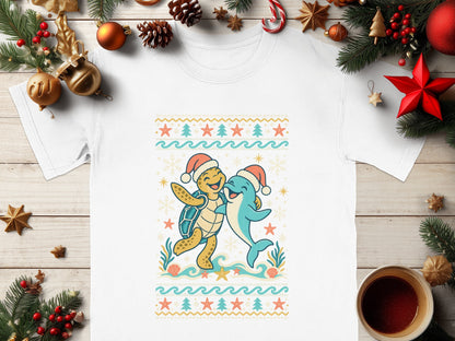 White t-shirt with a cartoon turtle and dolphin wearing Santa hats and hugging.