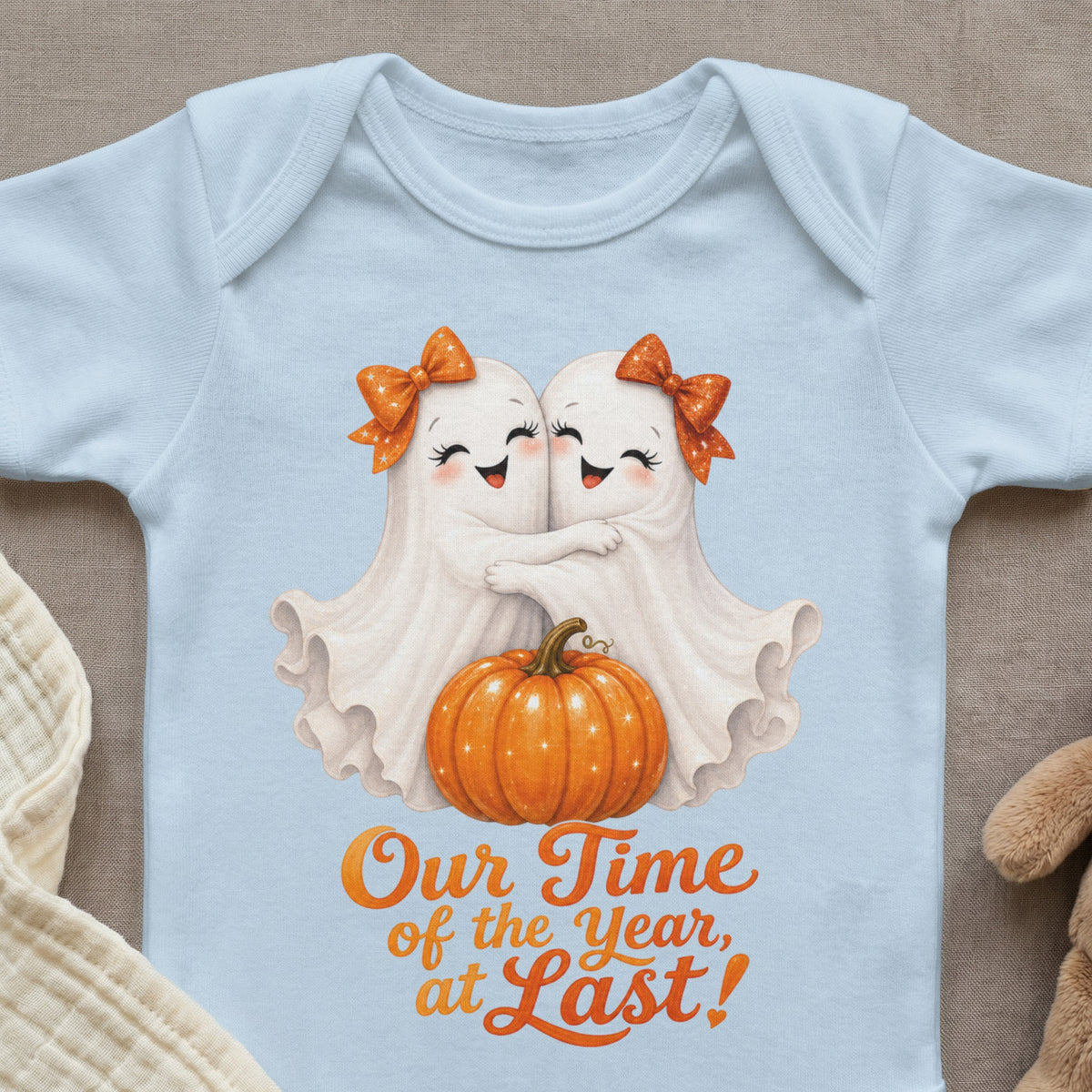 Light blue baby onesie with two ghosts hugging, a pumpkin, and text reading "Our Time of the Year, at Last!".