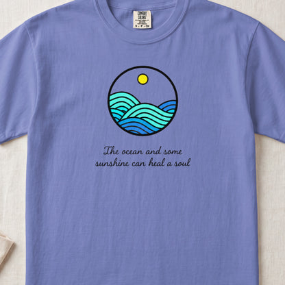 Purple t-shirt with a circular ocean and sun graphic and text.