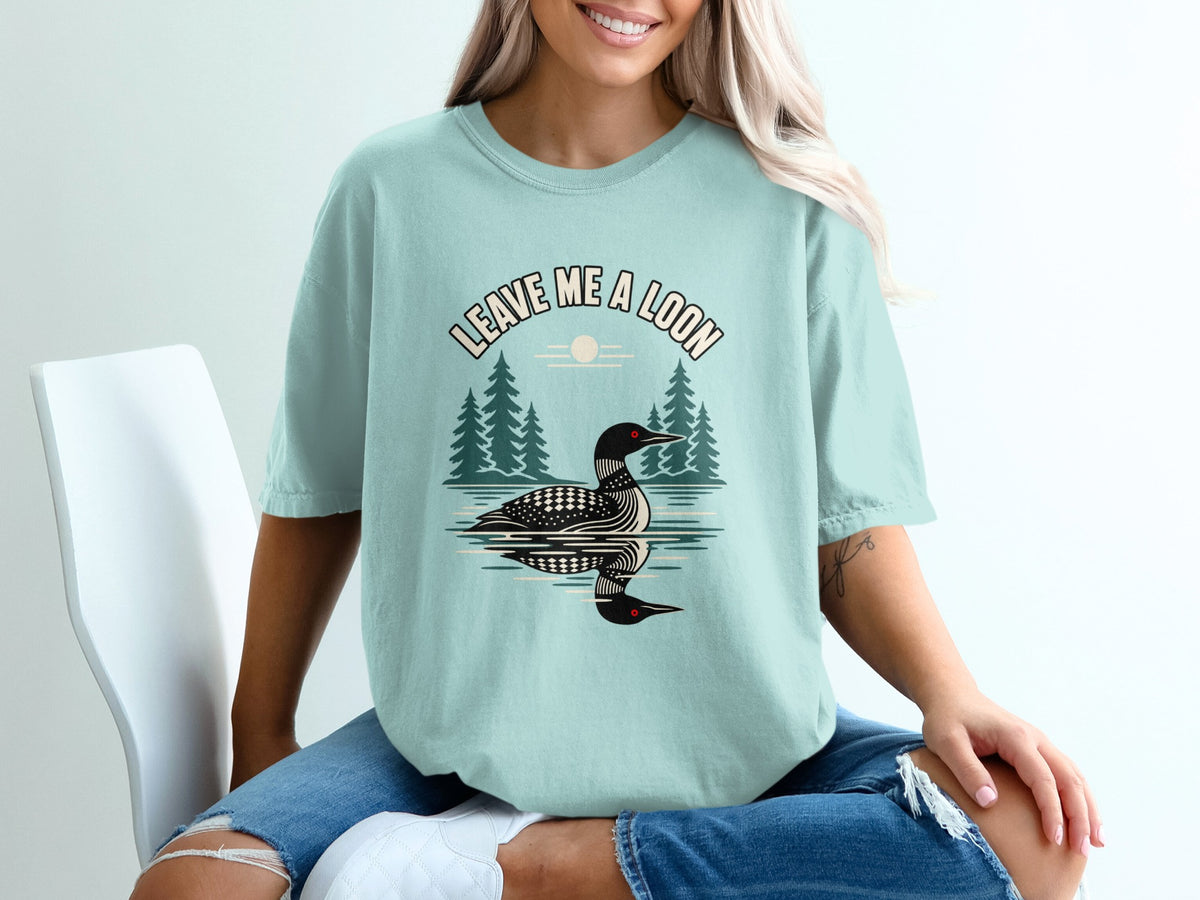 Light blue t-shirt with a graphic of a loon on water and text "LEAVE ME A LOON".