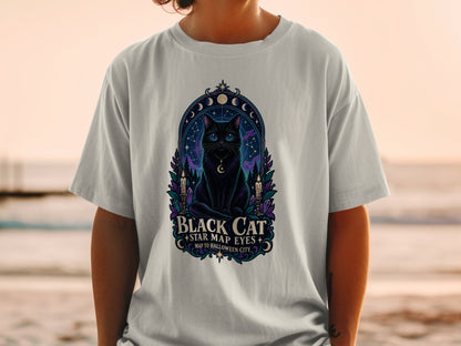 T-shirt graphic of a black cat with starry eyes, surrounded by moons, candles, and crystals.