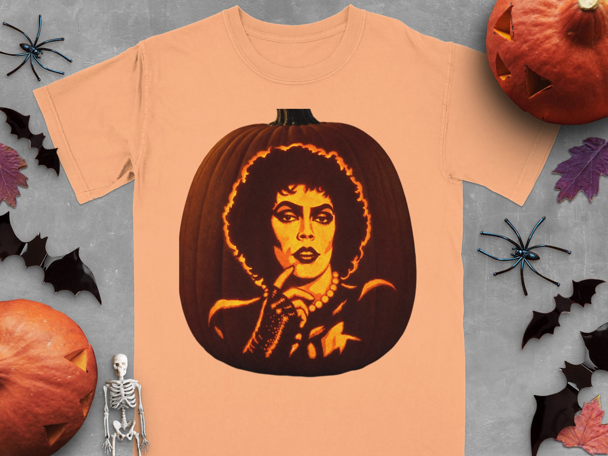 Peach t-shirt featuring a lit pumpkin carved with Dr. Frank-N-Furter from The Rocky Horror Picture Show, surrounded by Halloween decorations.