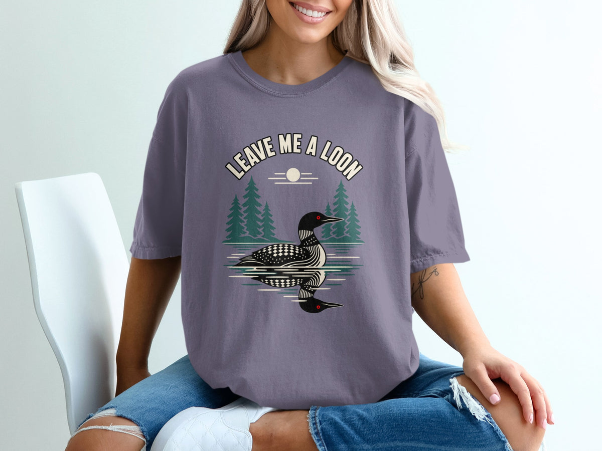 T-shirt graphic with loon, trees, and text "Leave Me A Loon".