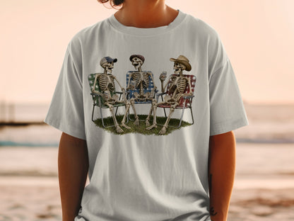 Three skeletons in lawn chairs, one with a hat and a drink, others with hats and cans.