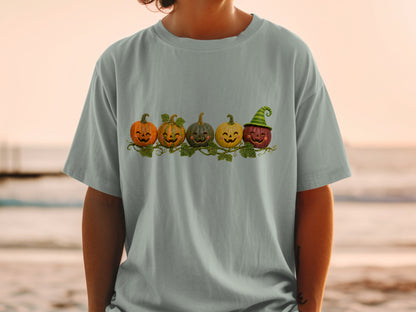 T-shirt with a line of five cartoon pumpkins, one wearing a witch hat.