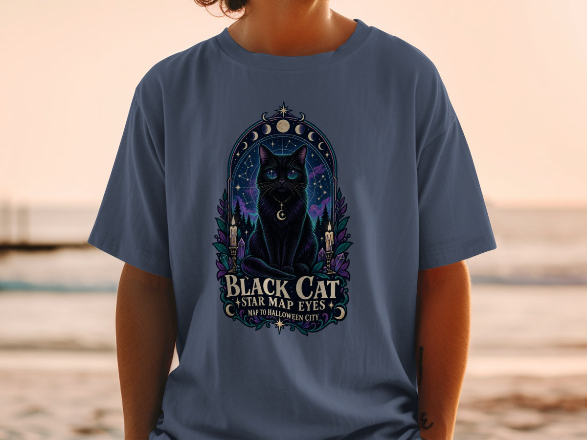 Black cat with star map eyes graphic on a blue t-shirt with text "Black Cat Map to Halloween City".