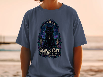 Black cat with star map eyes graphic on a blue t-shirt with text "Black Cat Map to Halloween City".