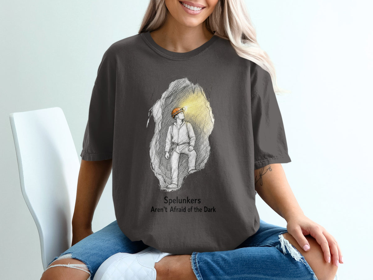 Dark grey t-shirt with sketch of spelunker in cave and text "Spelunkers Aren't Afraid of the Dark".