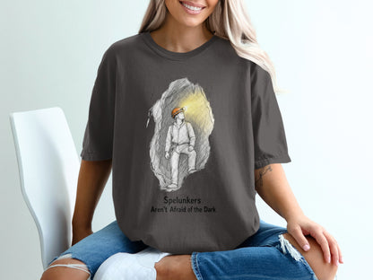 Dark grey t-shirt with sketch of spelunker in cave and text "Spelunkers Aren't Afraid of the Dark".