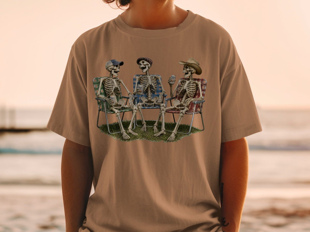 Three skeletons sit in lawn chairs holding drinks with a beach sunset in the background.