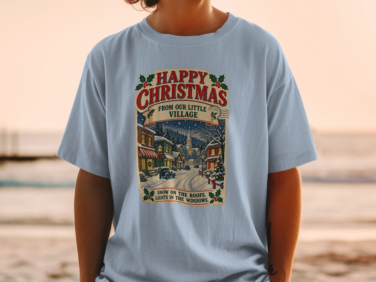 Light blue t-shirt with vintage Christmas village graphic and text.