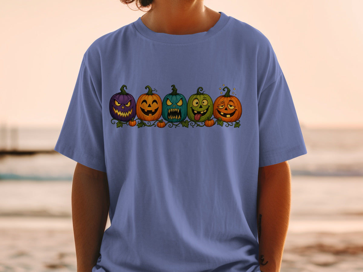 Five cartoon pumpkins with various expressions, displayed on a blue t-shirt.