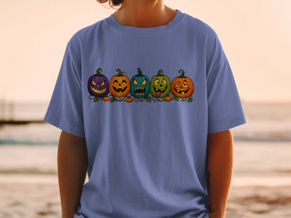 Five cartoon pumpkins with various expressions, displayed on a blue t-shirt.
