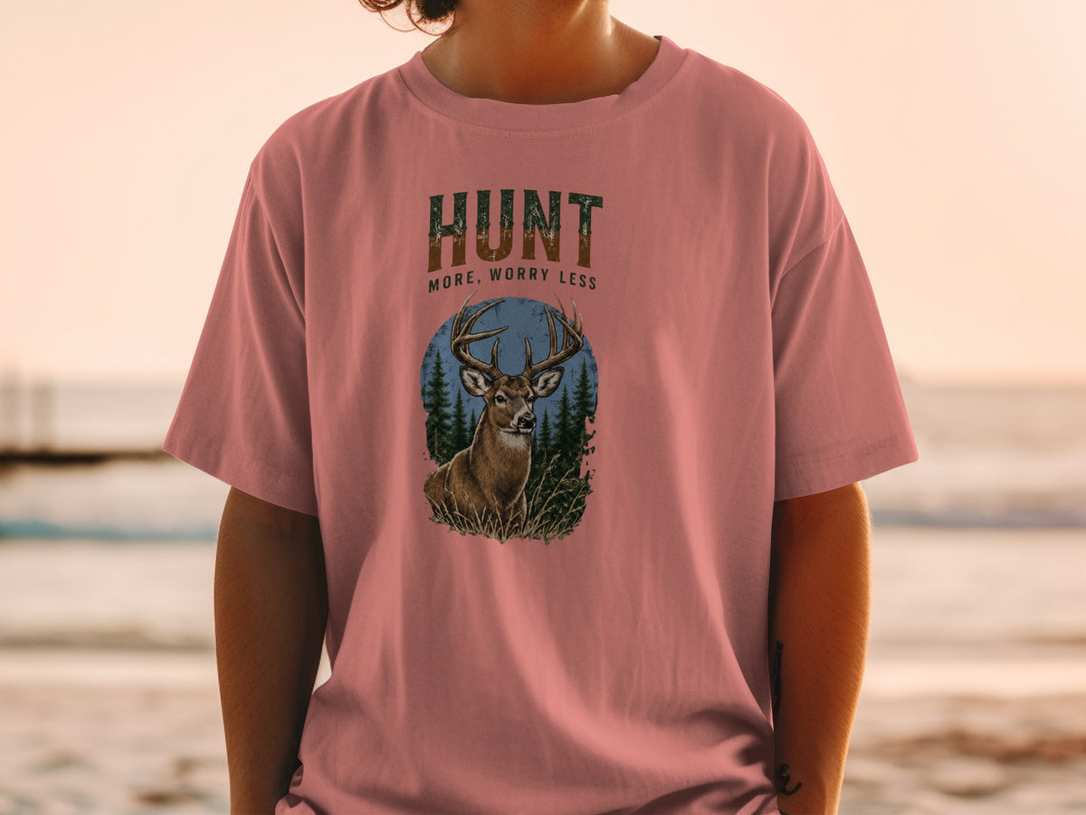 Pink t-shirt with deer and forest graphic, says "HUNT MORE, WORRY LESS".