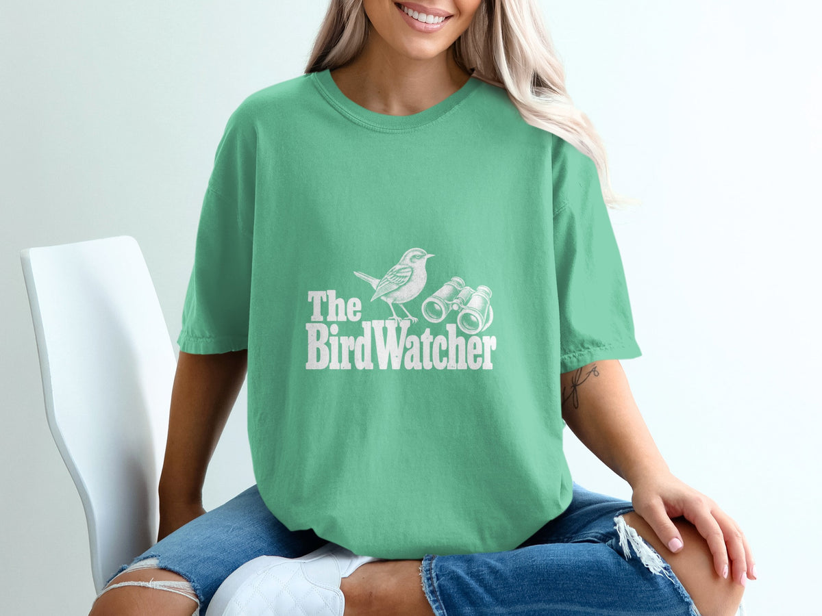 Green t-shirt with white bird and binoculars graphic, text "The BirdWatcher".