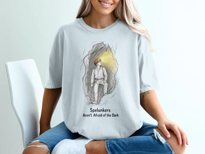 Light blue t-shirt with sketch of spelunker in cave and text "Spelunkers Aren't Afraid of the Dark".