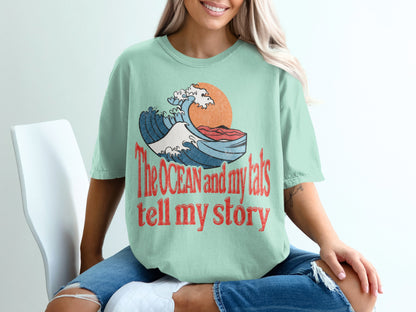 Mint green t-shirt with graphic and text reading "The OCEAN and my tats tell my story".
