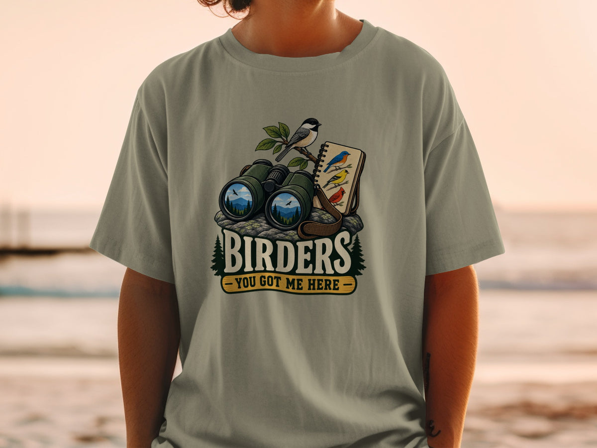 T-shirt graphic featuring binoculars, birds, and the text "BIRDERS - YOU GOT ME HERE".