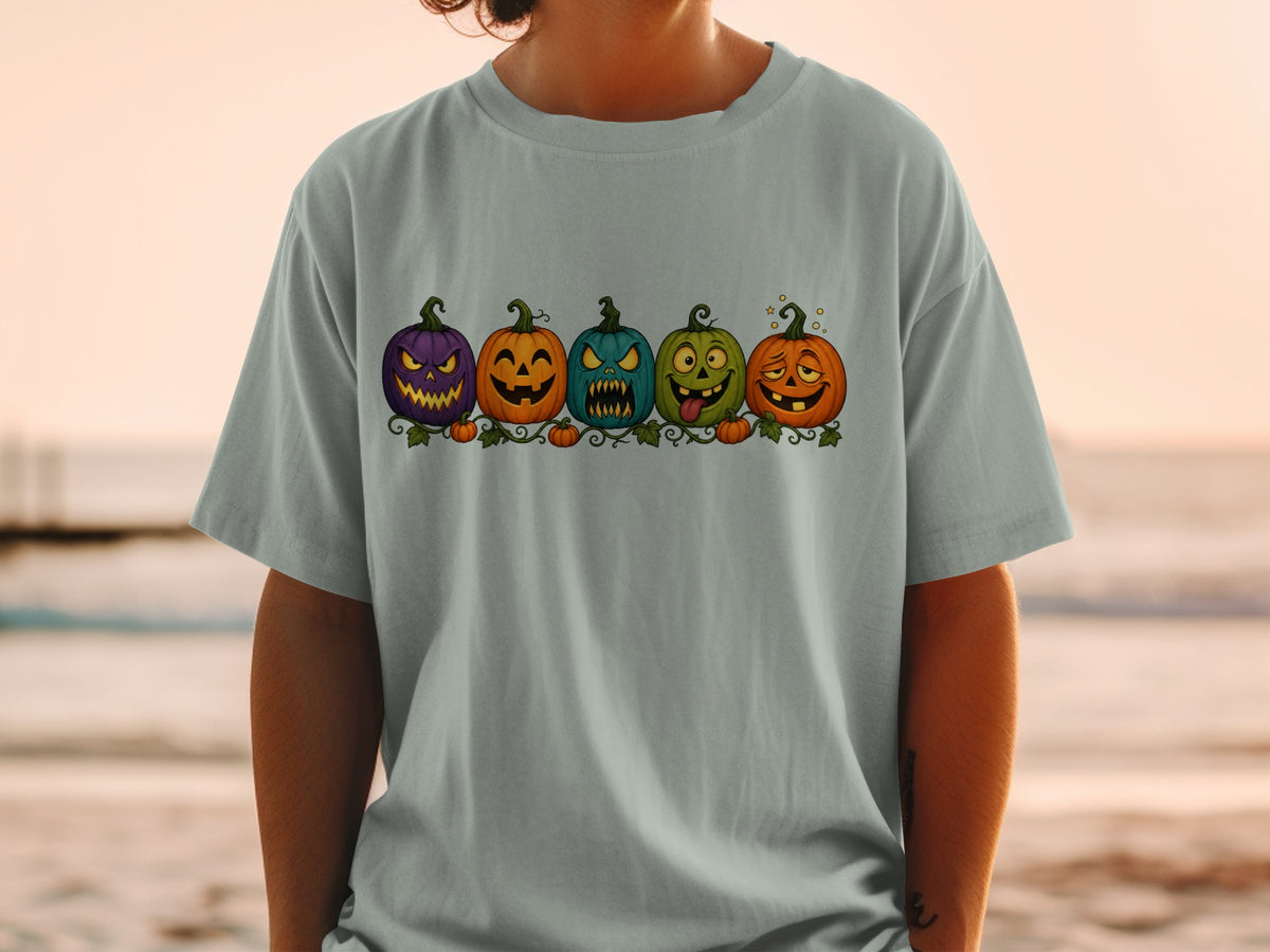 Line of five cartoon Halloween pumpkins with carved faces on a t-shirt.