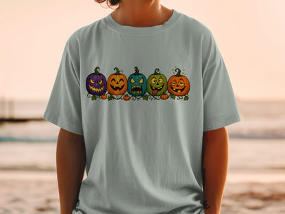 Line of five cartoon Halloween pumpkins with carved faces on a t-shirt.