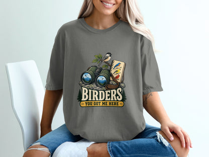 Graphic tee with binoculars, birds, notebook, and text "BIRDERS YOU GOT ME HERE".