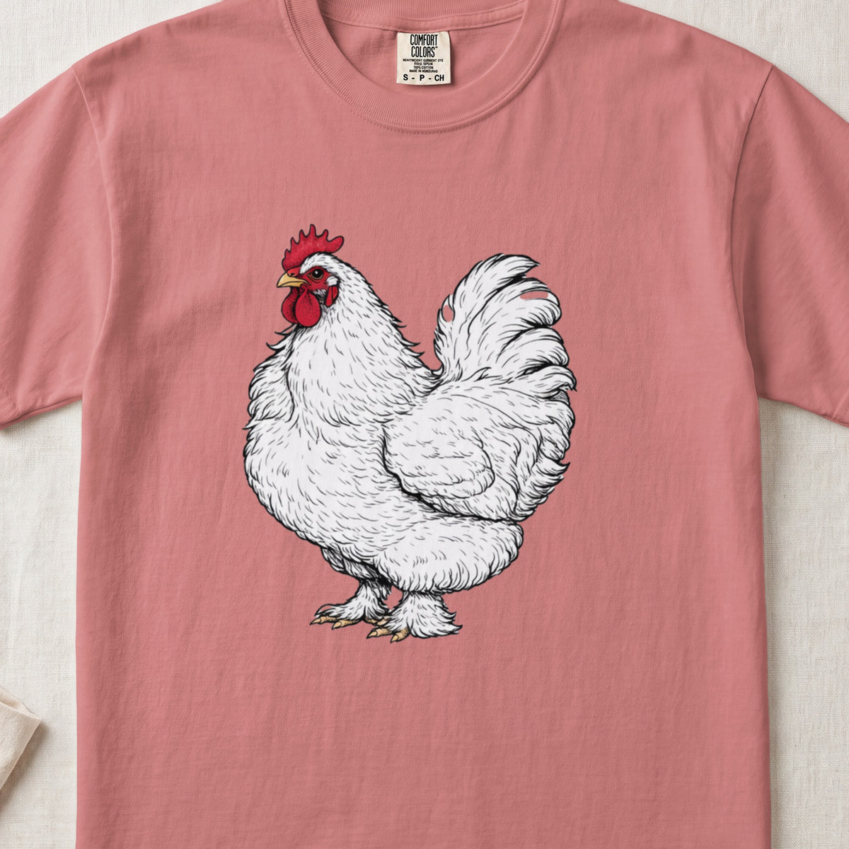 A pink crewneck t-shirt featuring an illustrated white rooster with a red comb.