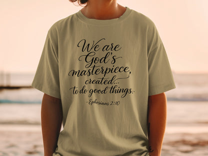 Khaki t-shirt with black script text: "We are God's masterpiece, created... to do good things. -Ephesians 2:10"