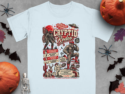 "Cryptid Rodeo" graphic with Bigfoot, Mothman, jackalope, and UFO on light blue t-shirt.