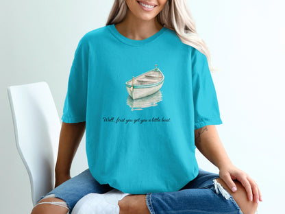 Turquoise t-shirt with watercolor painting of a rowboat and text: "Well, first you get you a little boat".