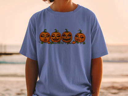 Four cartoon pumpkins with makeup are displayed in a line on a t-shirt.