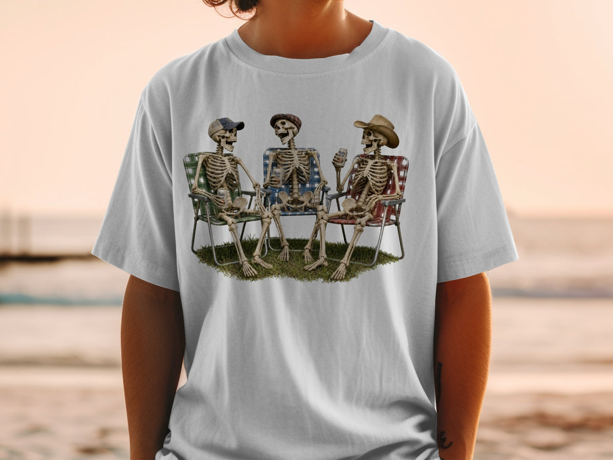 Three skeletons sit in lawn chairs holding drinks with a beach background.