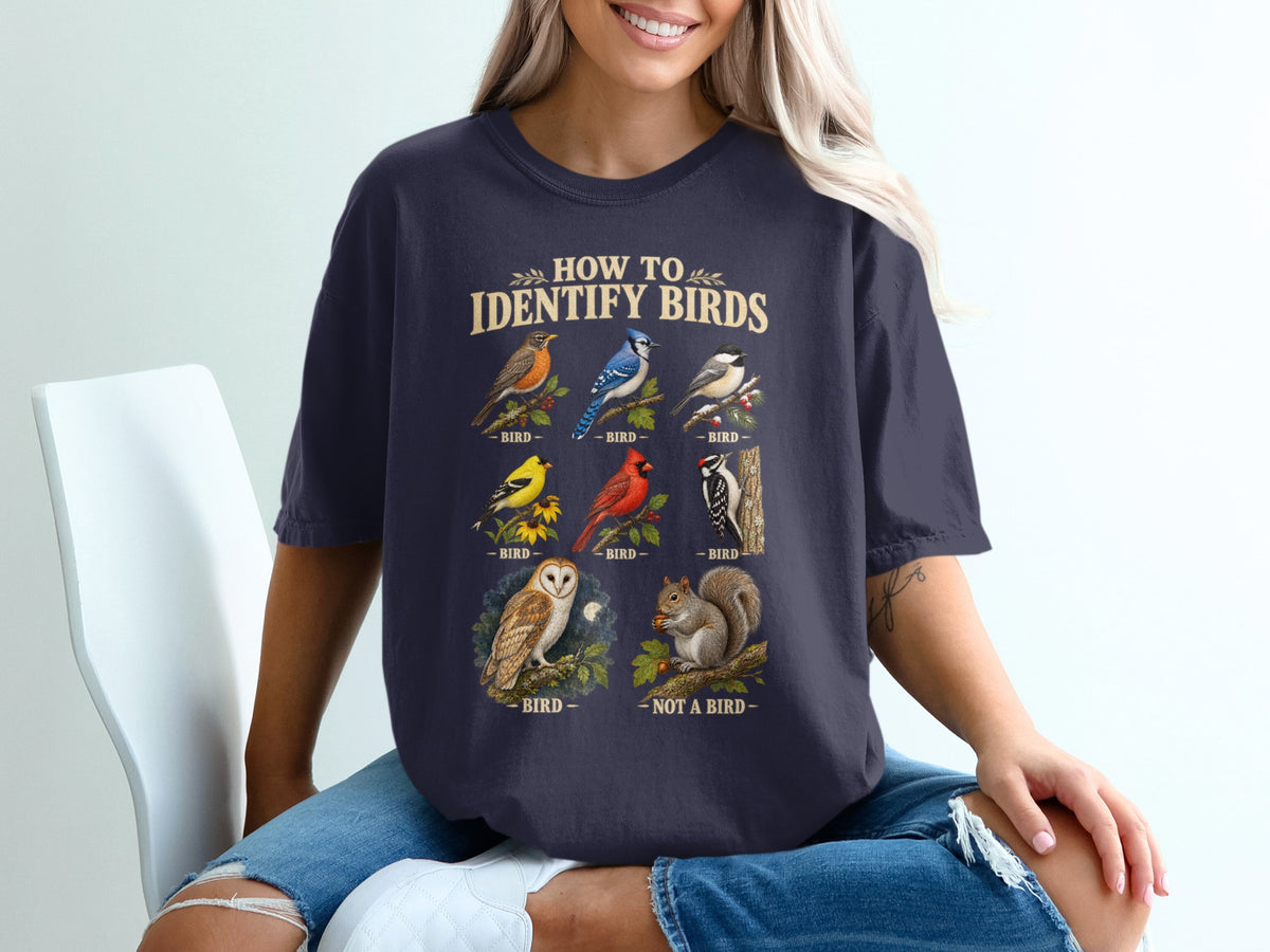 T-shirt graphic "How To Identify Birds" with illustrations of robin, blue jay, chickadee, finch, cardinal, woodpecker, owl, and squirrel.