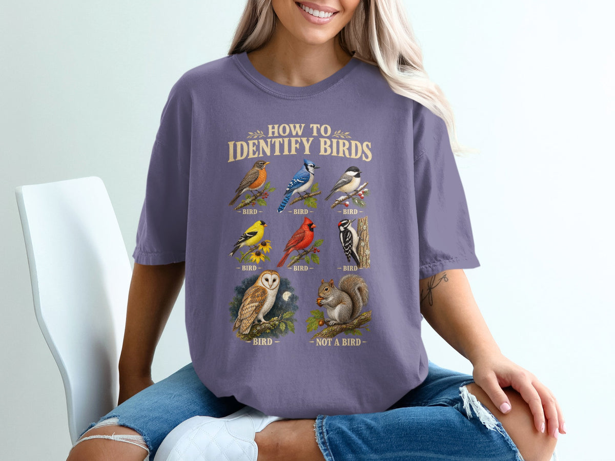 A person wearing a purple t-shirt featuring a funny vintage-style bird identification chart.