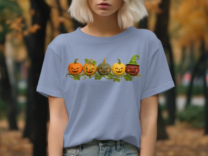 Five jack-o'-lanterns with carved faces on a vine on a light blue t-shirt.