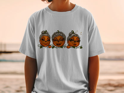 Three cartoon pumpkins with fashionable hairstyles and glasses on a white t-shirt.