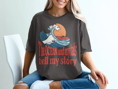 Dark gray t-shirt with wave graphic and text "The OCEAN and my tats tell my story".