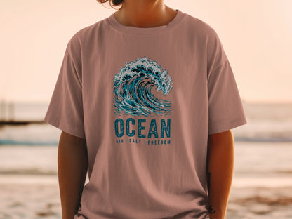 Pink t-shirt with a graphic of a breaking ocean wave and text "OCEAN AIR SALT FREEDOM".