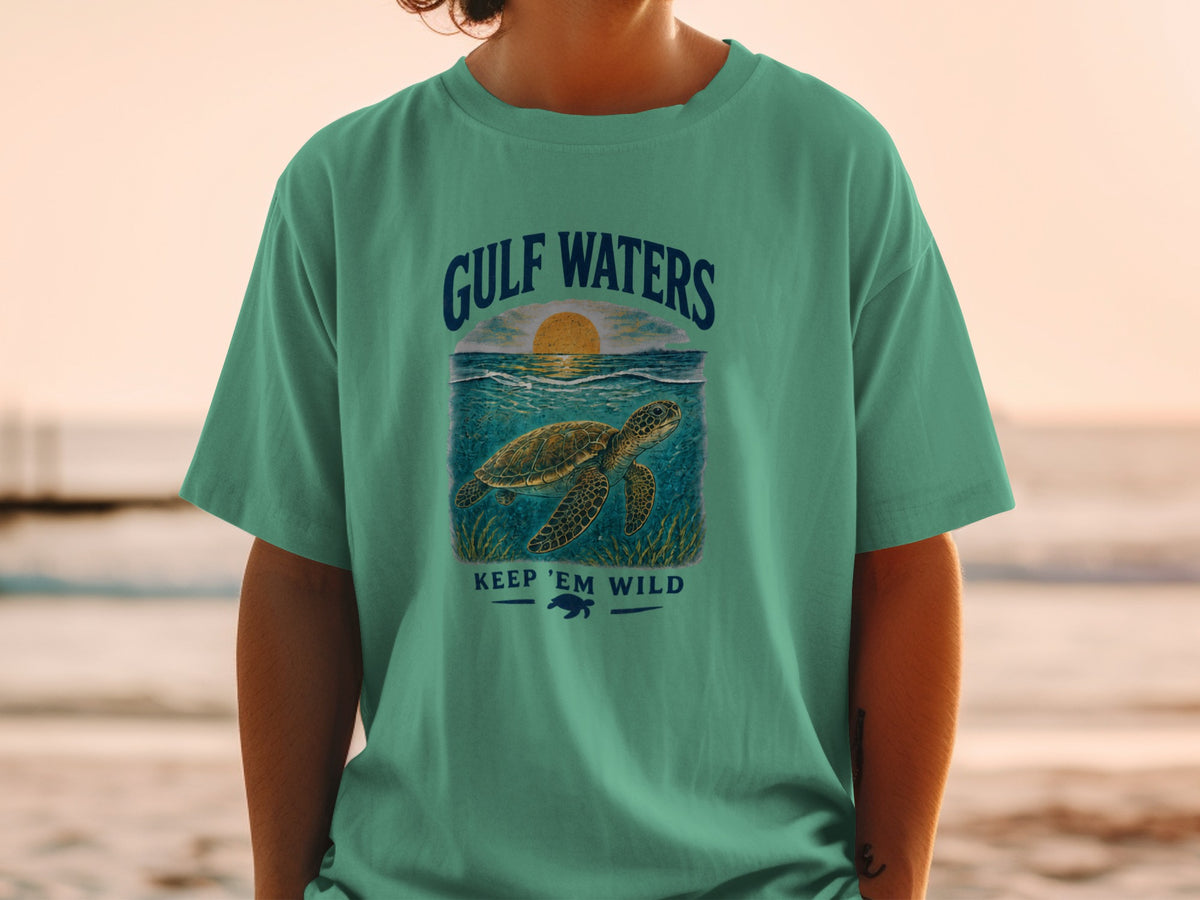 Green t-shirt with Gulf Waters design featuring a sea turtle and sunset.