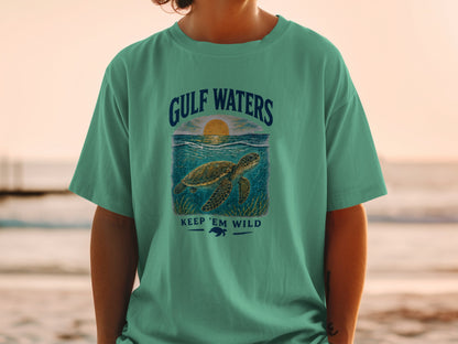 Green t-shirt with Gulf Waters design featuring a sea turtle and sunset.
