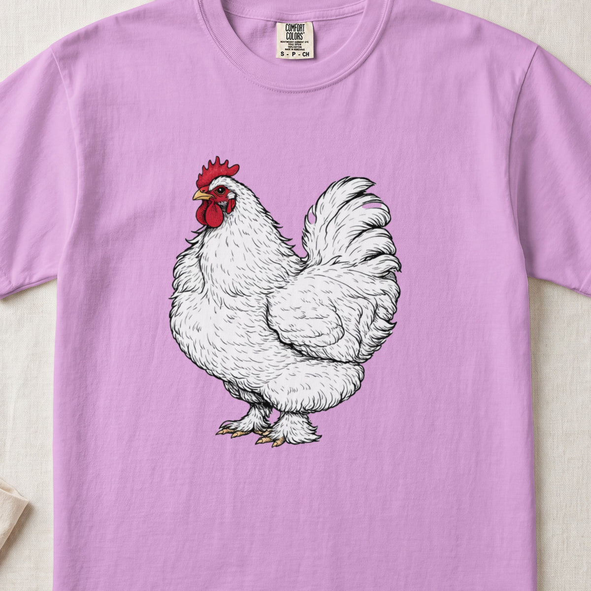 A pink t-shirt featuring a detailed illustration of a fluffy white rooster on the front.