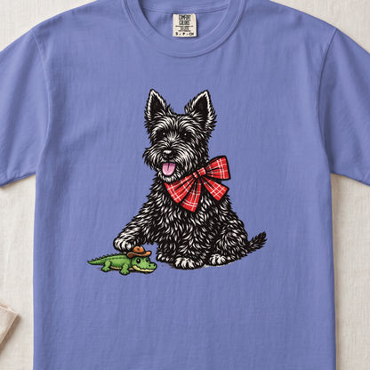 Periwinkle crewneck t-shirt featuring a black Scottish Terrier wearing a red plaid bow tie and touching a toy alligator.