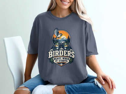 T-shirt with graphic of binoculars, bird, and mountains reading "BIRDERS READY WHEN IT STARTS."