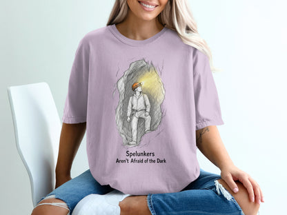 Lavender t-shirt with sketch of spelunker in cave and text: Spelunkers Aren't Afraid of the Dark.