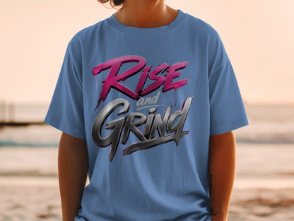 Blue t-shirt with "Rise and Grind" text in stylized pink and silver lettering.